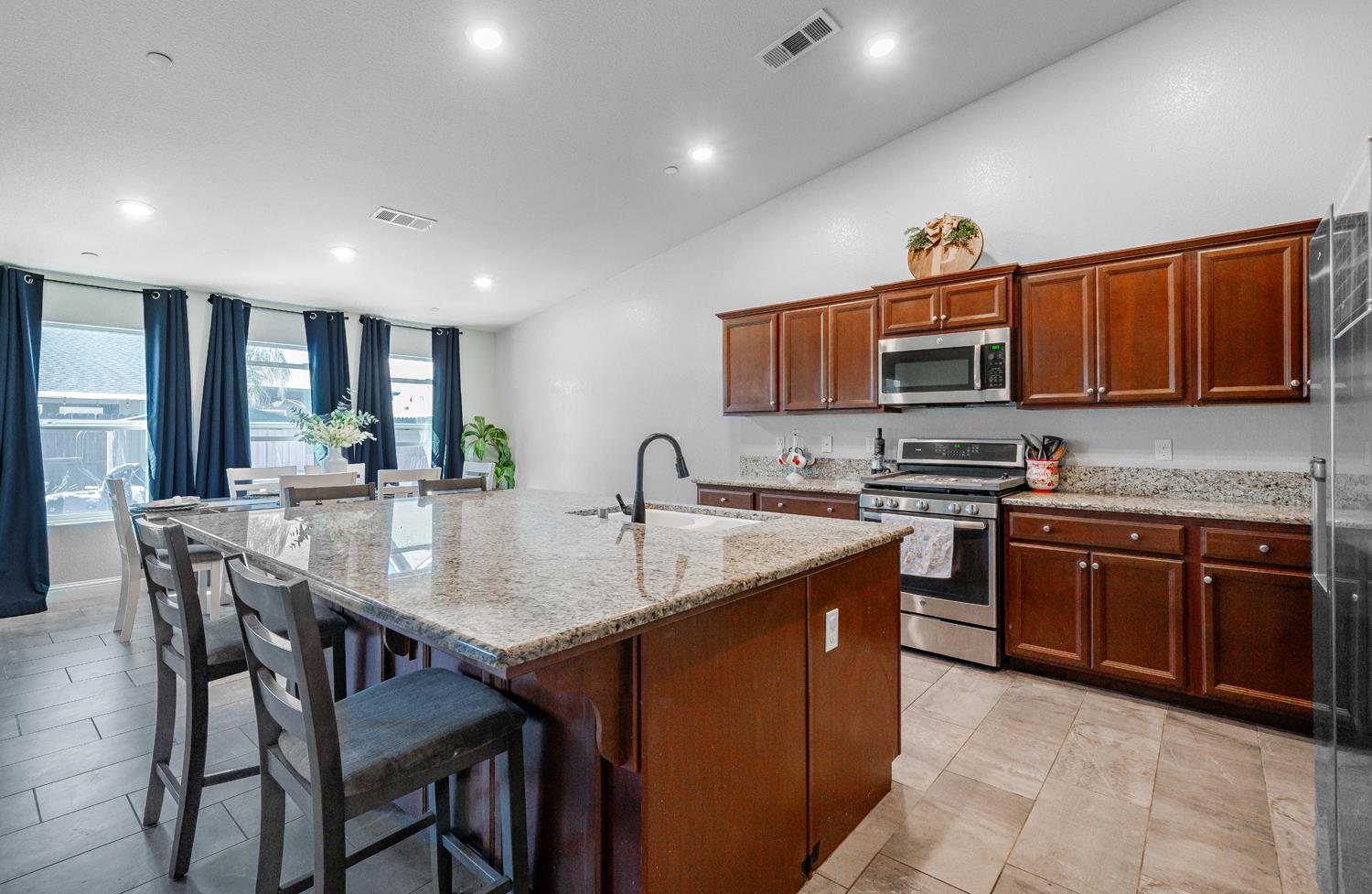 3133 4th Street Sanger, CA 93657 - Photo 16 of 33 a kitchen with stainless steel appliances granite countertop a stove a sink a microwave a dining table and chairs
