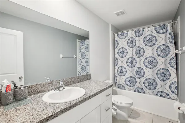 a bathroom with a granite countertop toilet sink and mirror