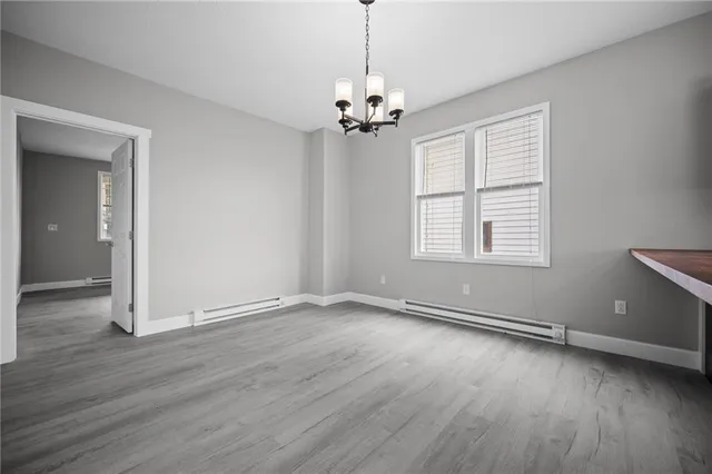 an empty room with wooden floor chandelier and windows