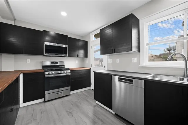 a kitchen with stainless steel appliances and view of living room
