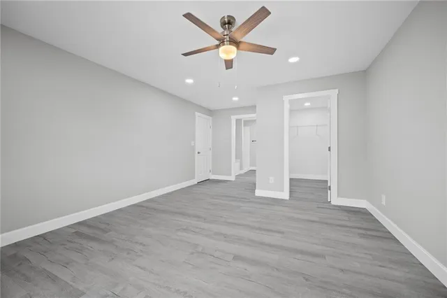 an empty room with wooden floor and ceiling fan