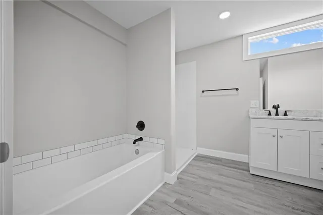 a bathroom with a tub sink and mirror
