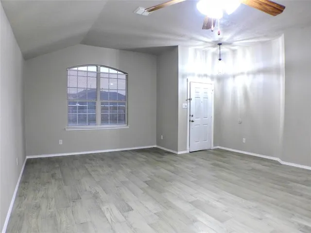 an empty room with wooden floor chandelier and windows