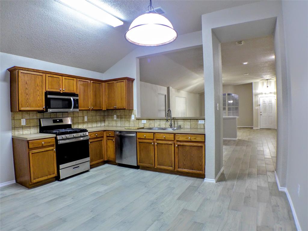 7300 Cresswell Drive Arlington, TX 76001 - Photo 6 of 20 a large kitchen with cabinets wooden floor and stainless steel appliances