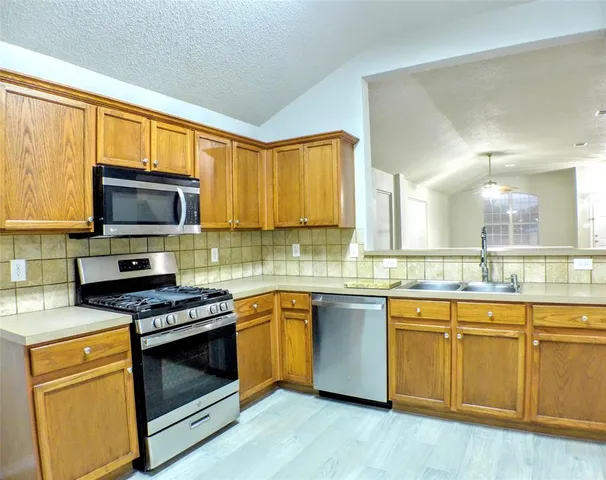 a kitchen with stainless steel appliances a stove a sink and a microwave
