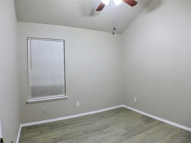 an empty room with a window and chandelier fan