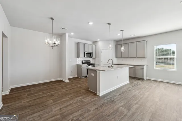 a large white kitchen with a refrigerator a sink dishwasher a stove and white cabinets with wooden floor