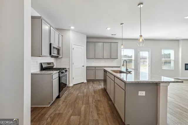 a kitchen with kitchen island granite countertop a sink a counter top space stainless steel appliances and cabinets
