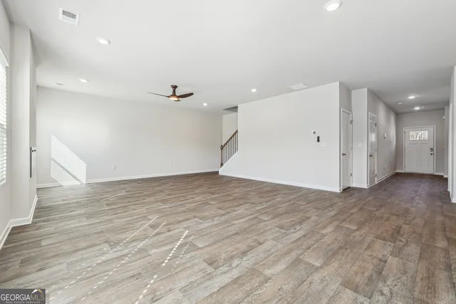 an empty room with wooden floor and a ceiling fan