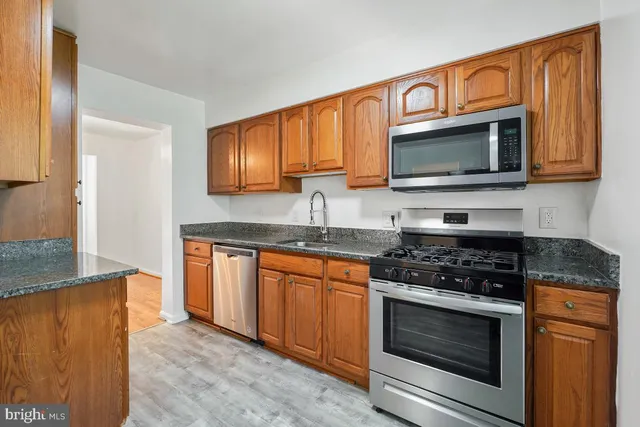 a kitchen with granite countertop wooden cabinets stainless steel appliances and a counter space