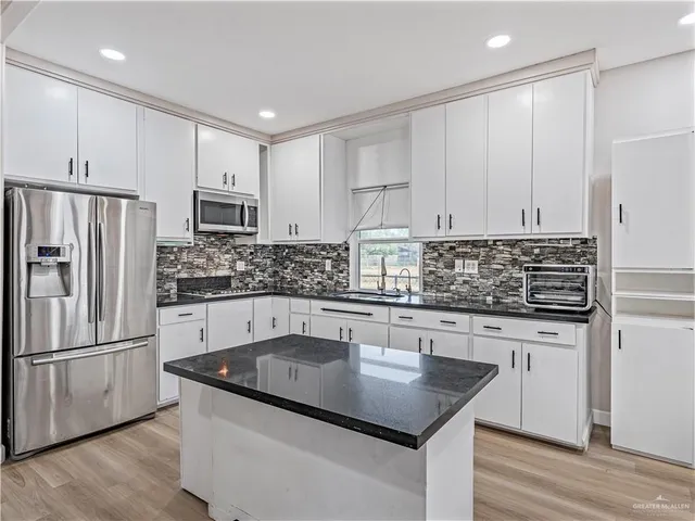a kitchen with kitchen island granite countertop a sink stove and refrigerator