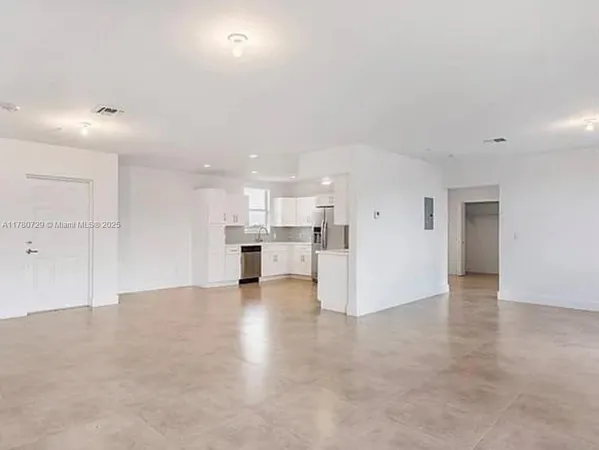 an empty room with kitchen and windows