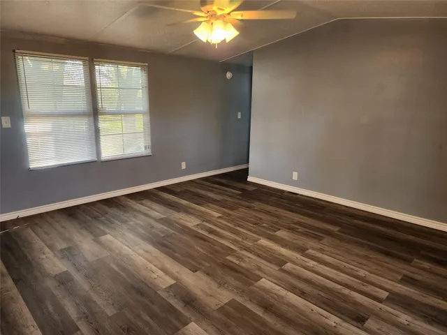a view of an empty room with window and wooden floor