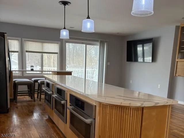 a dining room with wooden floor a chandelier a potted plant and windows