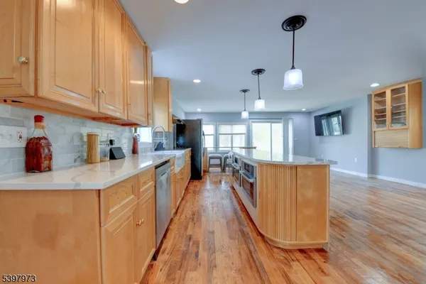 a large kitchen with stainless steel appliances granite countertop a stove a sink dishwasher and a refrigerator with wooden floor