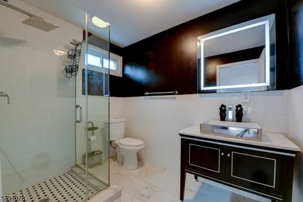 a bathroom with a sink a toilet a mirror and shower