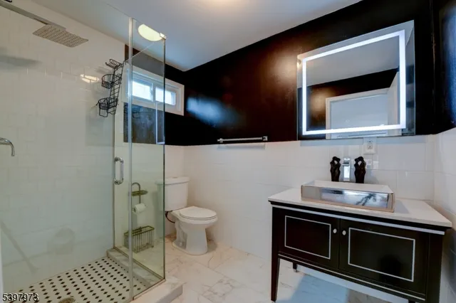a bathroom with a sink a toilet a mirror and shower