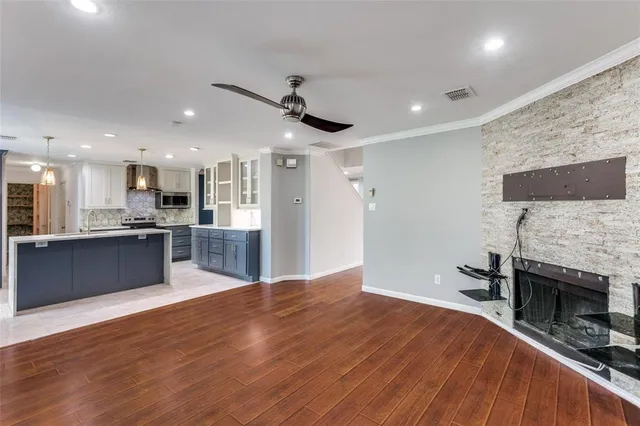 a large kitchen with stainless steel appliances kitchen island a large counter top a stove and a wooden floors