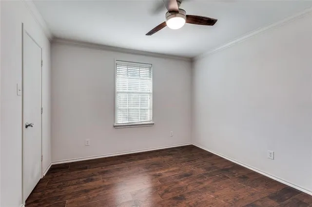 an empty room with wooden floor chandelier fan and windows