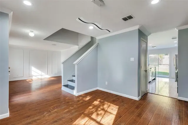 a view of a big room with wooden floor and windows