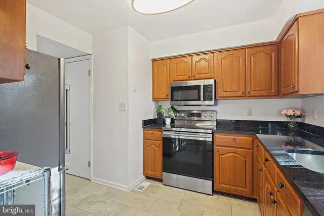 a kitchen with granite countertop wooden cabinets stainless steel appliances and a counter space