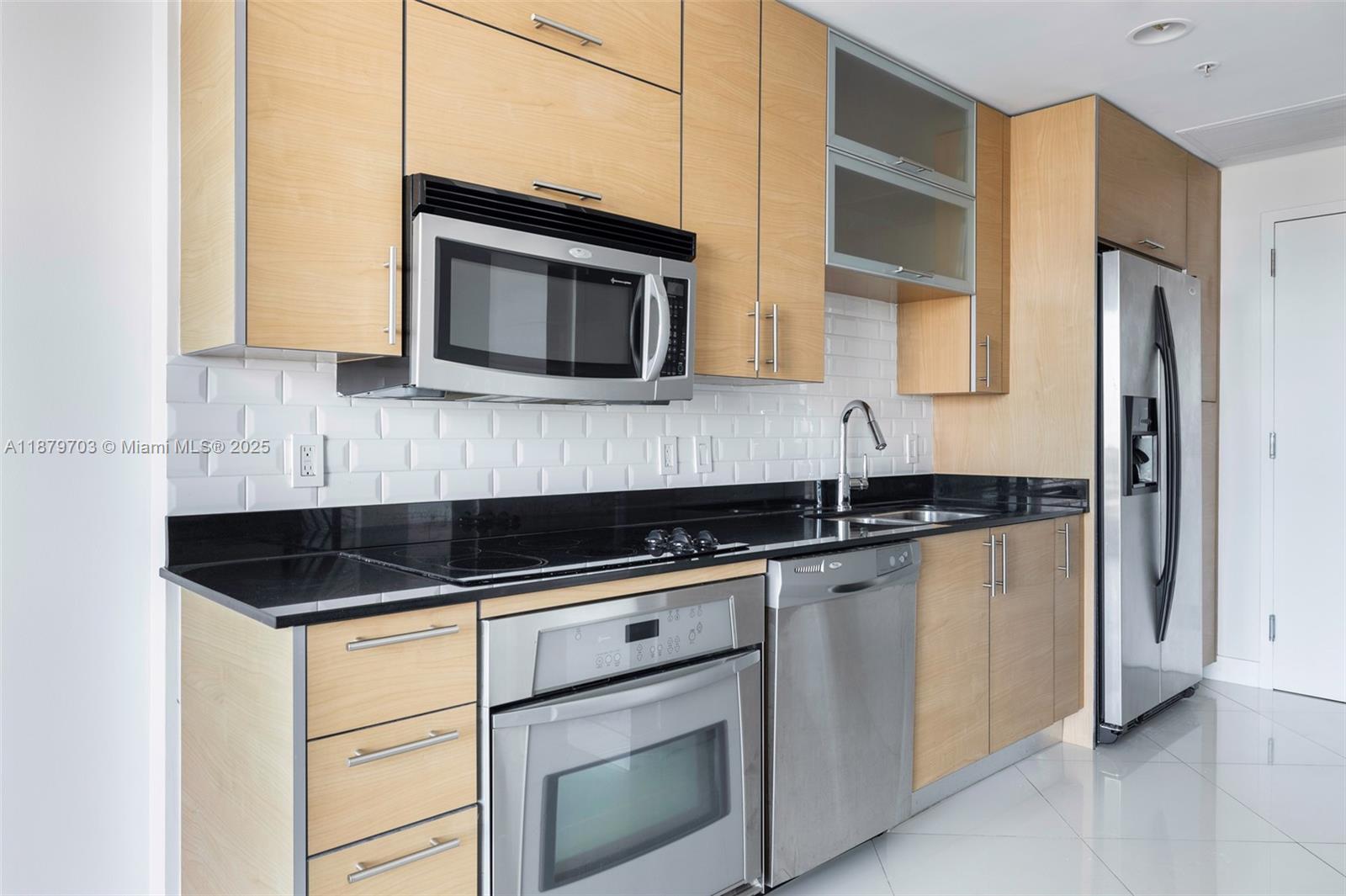 60 Southwest 13th Street, Unit 2413 Miami, FL 33130 - Photo 3 of 19 a kitchen with granite countertop white cabinets and black appliances