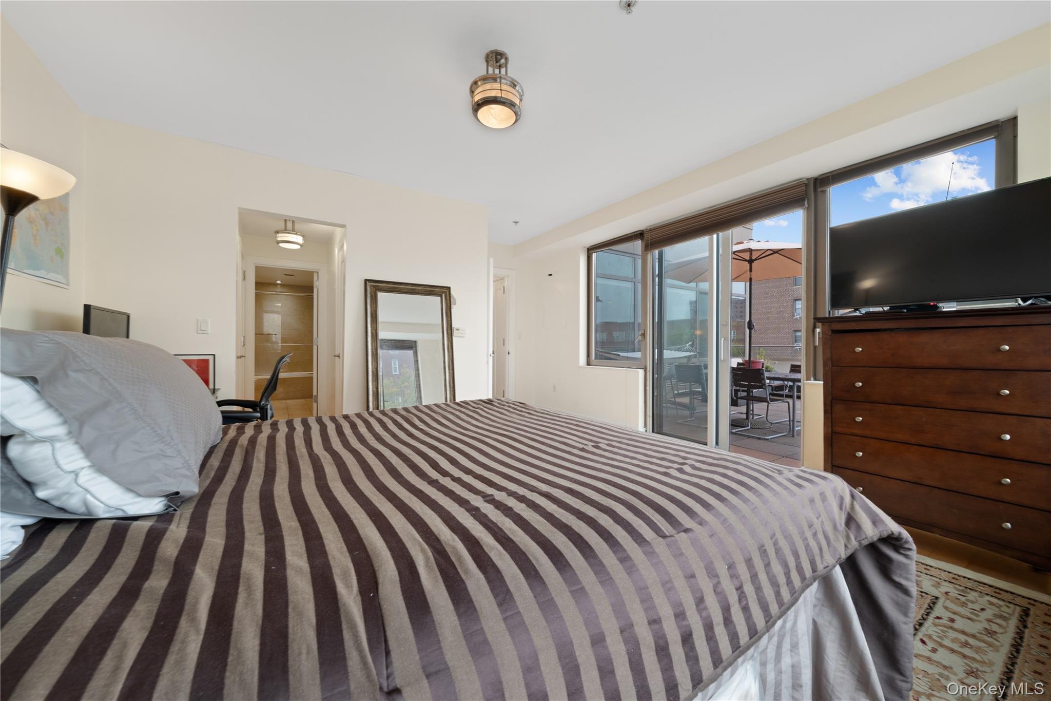 64-05 Yellowstone Boulevard, Unit PH 509 Queens, NY 11375 - Photo 10 of 28 a bedroom with a bed and a flat screen tv