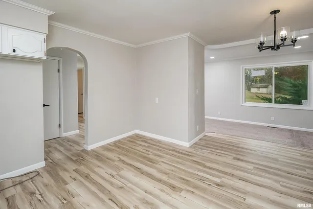 a view of an empty room with wooden floor windows and a chandelier