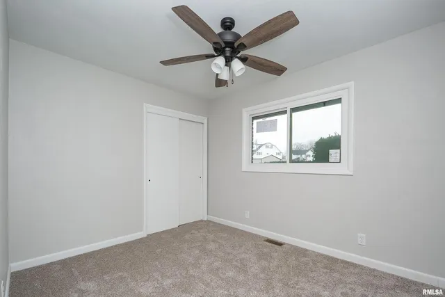 an empty room with a window and a ceiling fan