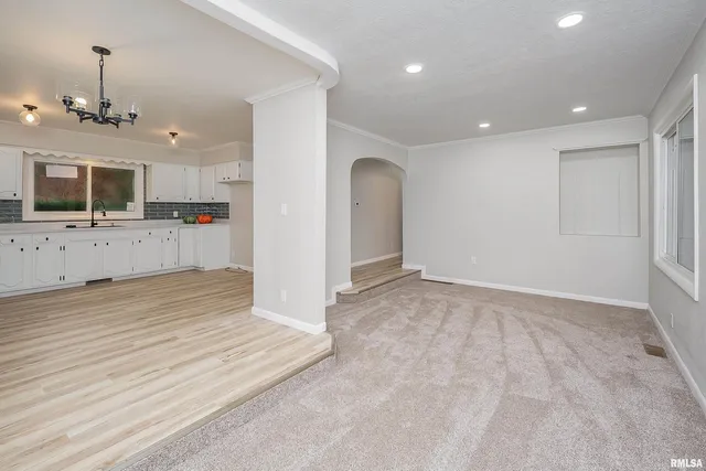 an empty room with kitchen view and wooden floor