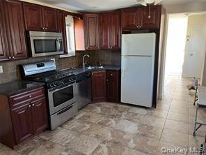 90 Murray Hill Street Elmont, NY 11003 - Photo 2 of 6 a kitchen with a refrigerator stove and microwave