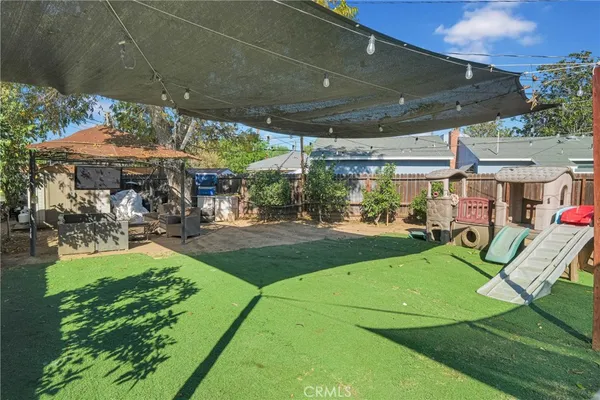 a view of a patio with table and chairs under an umbrella next to a yard
