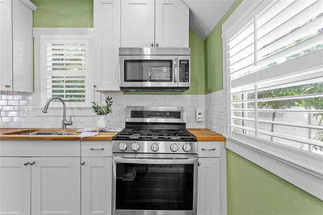 a kitchen with stainless steel appliances granite countertop a sink a stove and a window