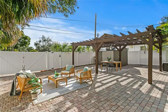 a view of a patio with table and chairs under an umbrella with potted plants
