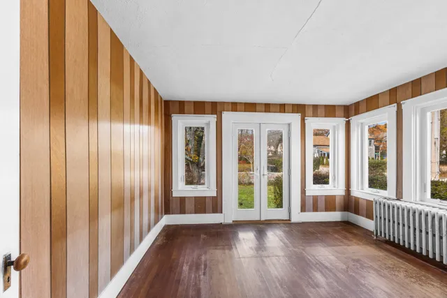 an empty room with wooden floor and windows