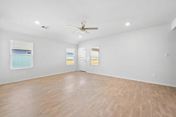 an empty room with windows and ceiling fan