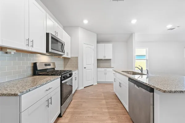 a large kitchen with stainless steel appliances granite countertop a stove a sink and a microwave