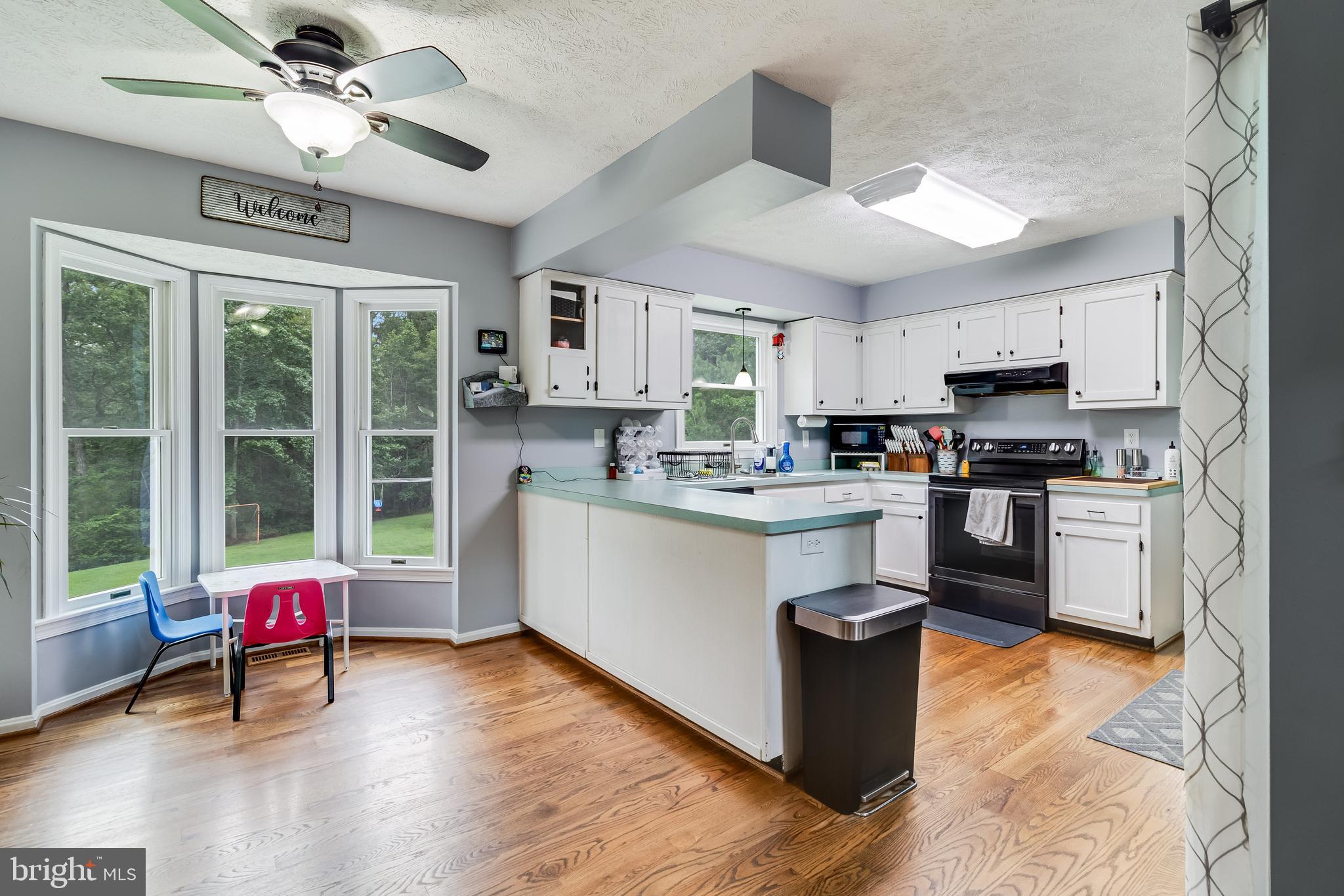 20919 Ridge Path Way Leonardtown, MD 20650 - Photo 32 of 56 a kitchen with stainless steel appliances granite countertop a stove top oven a sink dishwasher a dining table and chairs with wooden floor