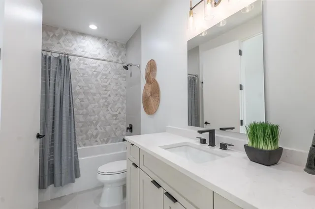 a bathroom with a granite countertop sink a toilet a shower and a mirror