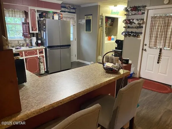 a kitchen with kitchen island a counter top space a sink wooden floor and a refrigerator