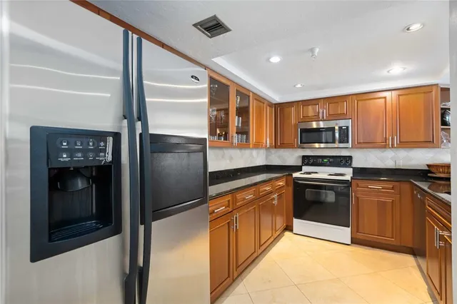 a kitchen with stainless steel appliances granite countertop a refrigerator and a stove top oven
