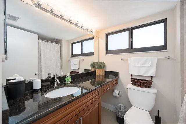 a bathroom with a granite countertop toilet sink and mirror
