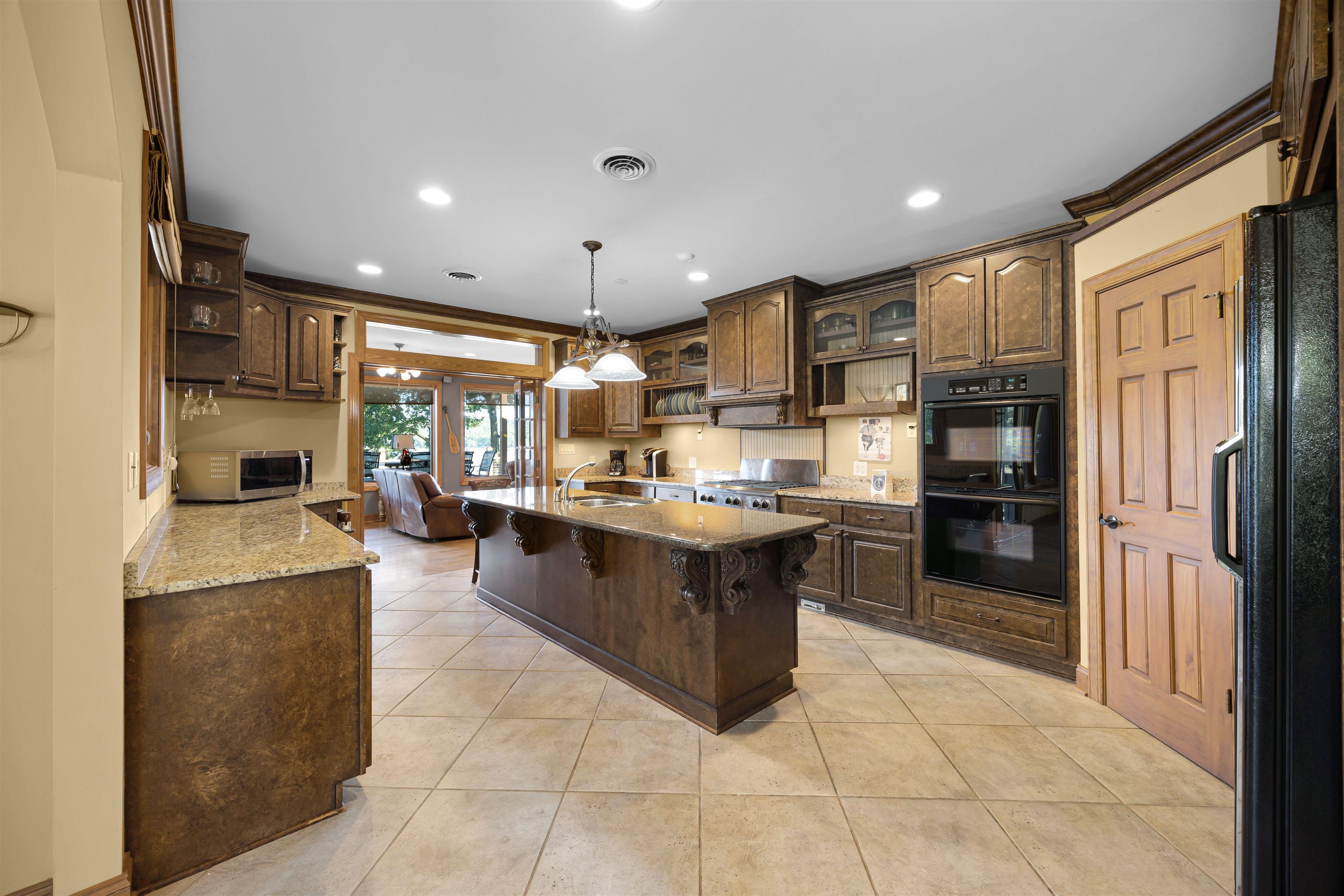 830 Big Bear Creek Road Cherokee, MS 35616 - Photo 13 of 39 Kitchen featuring pendant lighting, light tile patterned flooring, sink, black appliances, and a kitchen breakfast bar