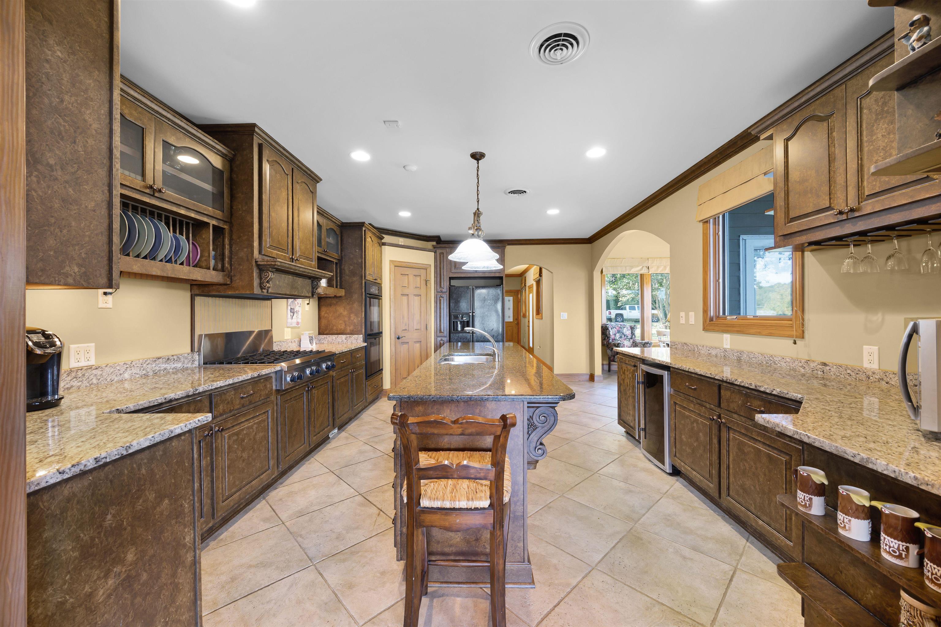 830 Big Bear Creek Road Cherokee, MS 35616 - Photo 25 of 39 Kitchen featuring stainless steel gas cooktop, light stone counters, an island with sink, ornamental molding, and light tile patterned floors