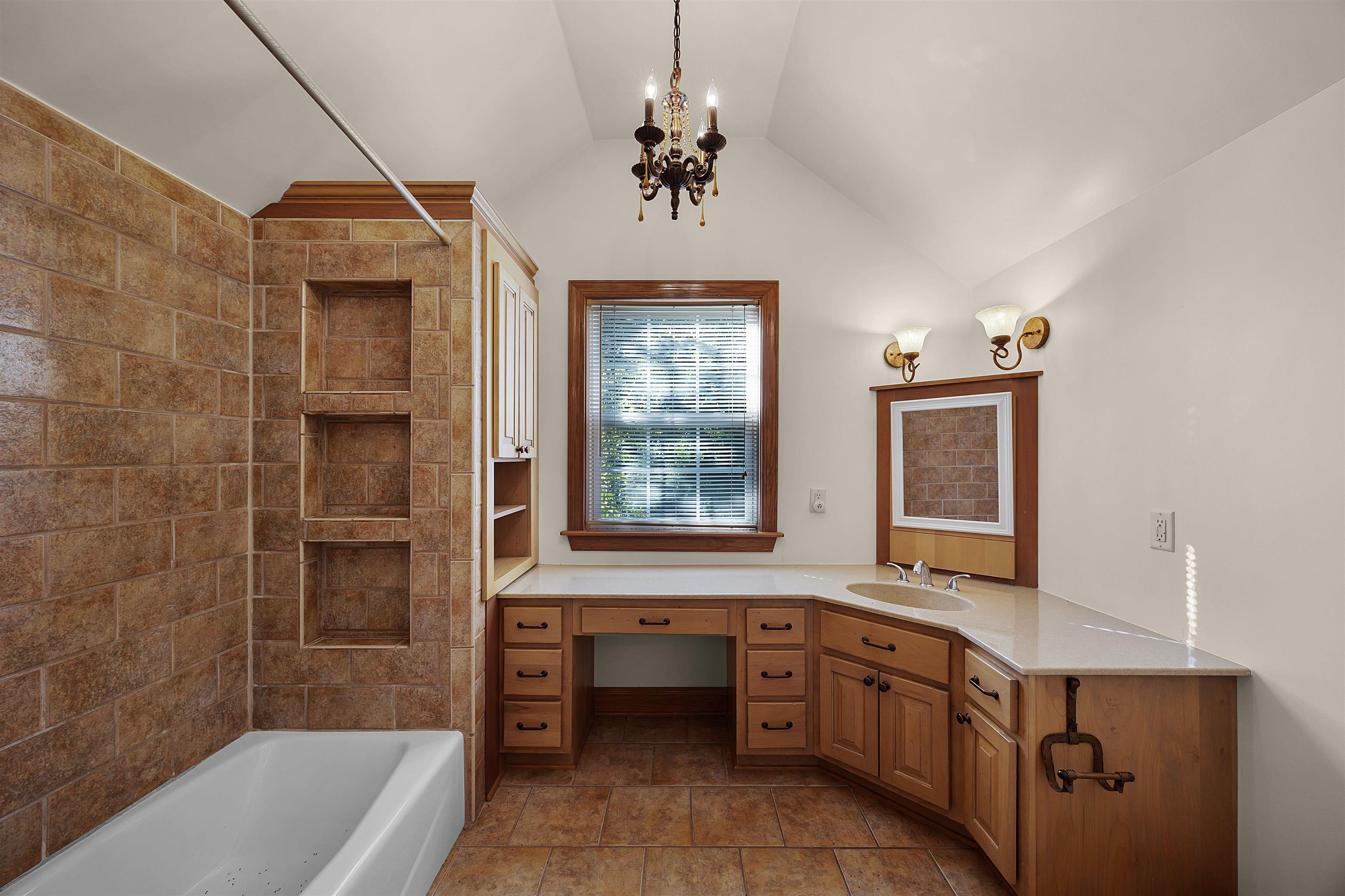 830 Big Bear Creek Road Cherokee, MS 35616 - Photo 32 of 39 Bathroom with lofted ceiling, vanity, a chandelier, and tiled shower / bath combo