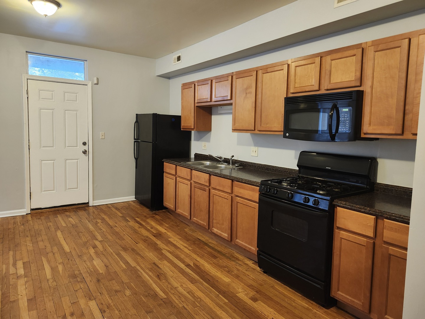 8016 South Ingleside Avenue, Unit 2S Chicago, IL 60619 - Photo 7 of 8 a kitchen with granite countertop wooden cabinets a stove top oven and stainless steel appliances