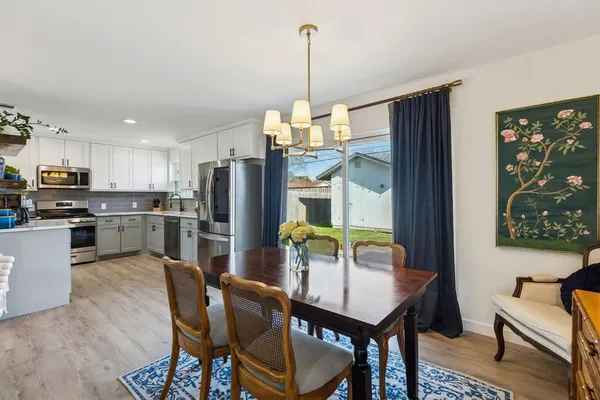a dining room with furniture a chandelier and kitchen view