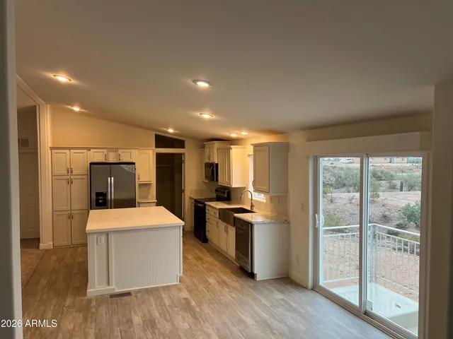 a large kitchen with a stove a refrigerator a sink a dining table and chairs with wooden floor