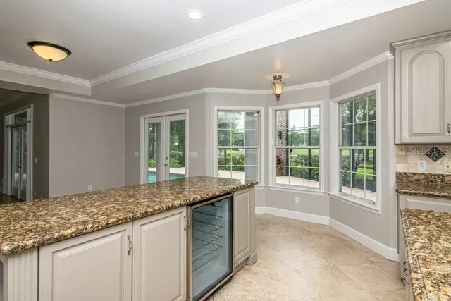 an empty room with wooden floor chandelier fan and windows