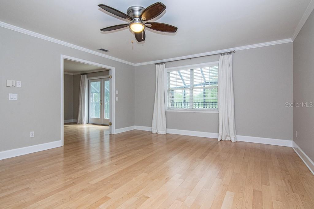 16405 Avila Boulevard Tampa, FL 33613 - Photo 25 of 61 an empty room with wooden floor chandelier fan and windows